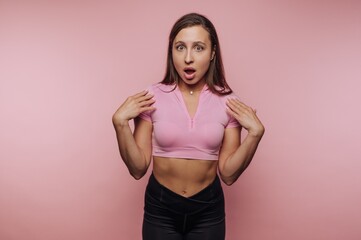 Surprised woman in a pink top against a pink background.