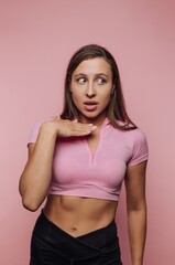 Woman in pink top looking surprised against pink background
