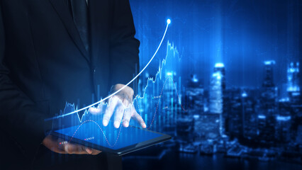 A businessman interacts with a tablet displaying financial data, highlighting a rising graph...