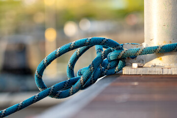 Securely Fastened Blue Rope Wrapped Around Metal Bollard on Wooden Dock, Nautical Knot Holding Boat in Place at Marina