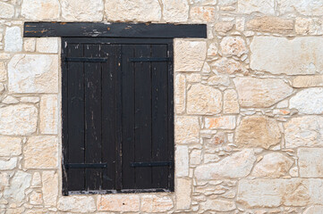 Weathered Black Shutters Are Beautifully Set Against a Gorgeous and Textured Stone Wall