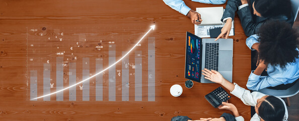 A focused business team analyzes financial data and growth strategies using a laptop and charts...