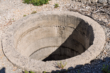 Abandoned concrete well in rocky landscape under sunlight