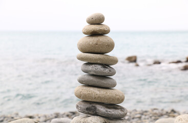 Balanced stones stacked on the beach with calm sea background, symbolizing harmony, balance, and mindfulness in nature. Perfect concept for wellness, meditation, and tranquility themes.