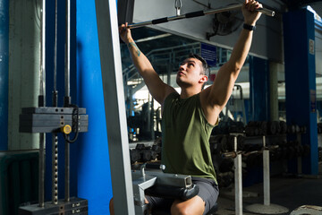 Active man exercising using lat pulldown machine in gym