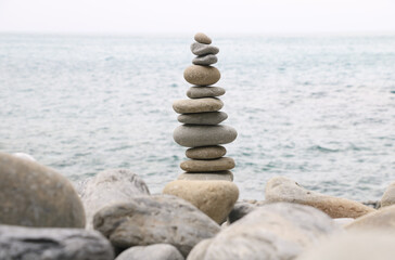 Balanced stones stacked on the beach with calm sea background, symbolizing harmony, balance, and mindfulness in nature. Perfect concept for wellness, meditation, and tranquility themes.