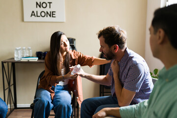 Woman offering comfort to man in group therapy session