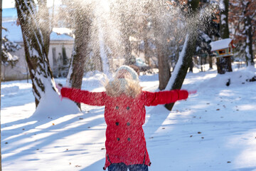  girl throws snow up. New Year and Christmas scene. child in the winter. Winter holidays concept. Blurred photo