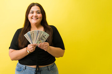 Happy plus size woman holding cash dollars
