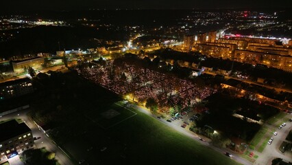 Fototapeta premium Aerial view of a Polish cemetery on All Saints’ Night, glowing with thousands of candles that honor the dead and illuminate the darkness with warmth and faith.