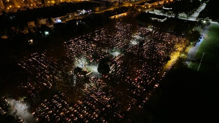 Aerial view of a Polish cemetery on All Saints’ Night, glowing with thousands of candles that...