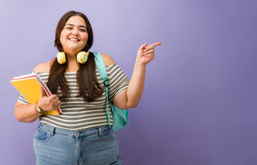 Happy plus size student pointing showing copy space