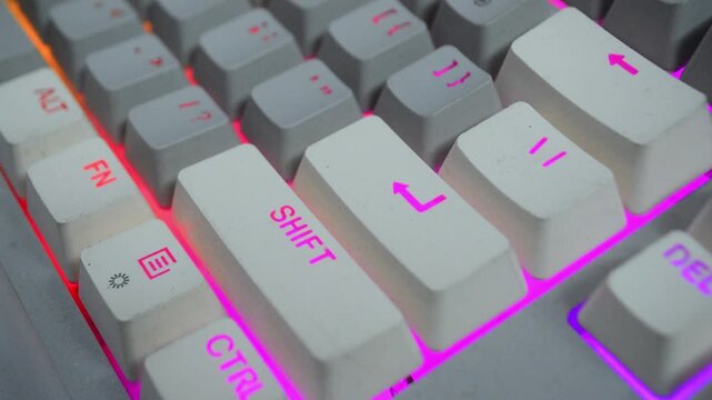 The index finger presses the Enter key on a computer keyboard with rgb light. A man's finger hovers over the Enter key for a few seconds before deciding to press it. The concept of yes or no. 