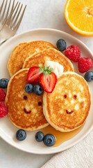 Child Friendly Meals Delicious pancakes with smiling faces topped with fruit and syrup on a plate.