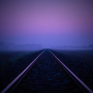 Long steel rails of the railroad track stretch into the horizon, a lonely path through the landscape at morning and night, inviting travel and a long journey