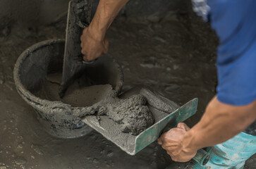 Hand worker mix cement plaster wall background with bucket trowel tool construction house site,...