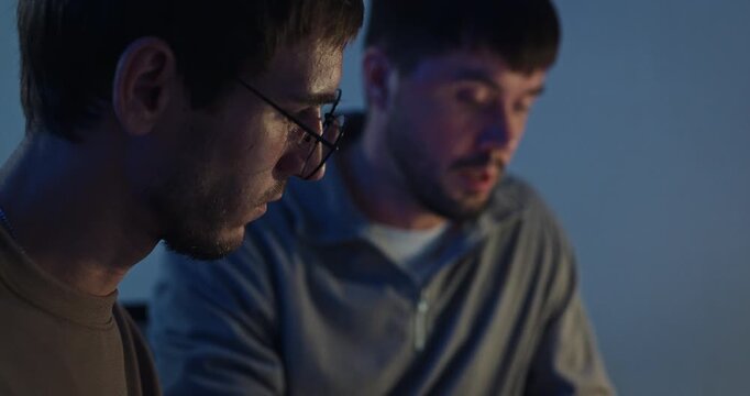 Closeup team adult male engineer collaborate on robotic hand project use AI code solutions machine learn at tech workspace night. Artificial intelligence interface collaboration prototype development.