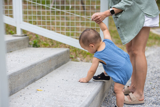 Mother helping baby walk up stone stairs