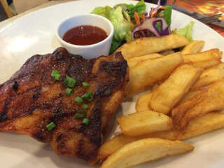 A serving of grilled chicken  with fries, salad and dipping sauce
