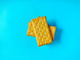 a stack of golden biscuits with a sprinkling of sugar is served on a bright blue background.
