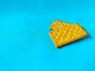 a stack of golden biscuits with a sprinkling of sugar is served on a bright blue background.