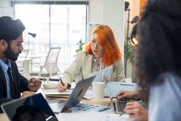 Multi-ethnic business team in office meeting, reviewing documents and brainstorming innovative...