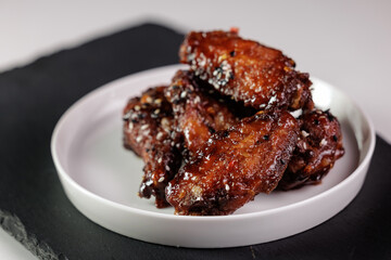 Spicy glazed chicken wings on white plate with sesame seeds