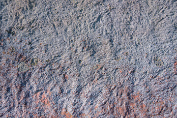 A close-up view reveals the intricate textures and colors of weathered stone in natural daylight. Various shades mingle, showcasing the beauty of nature's artistry