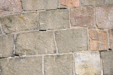 This scene features a close-up view of an ancient stone wall displaying diverse stone shapes and earthy colors. The sunlight highlights the textures and details of each stone