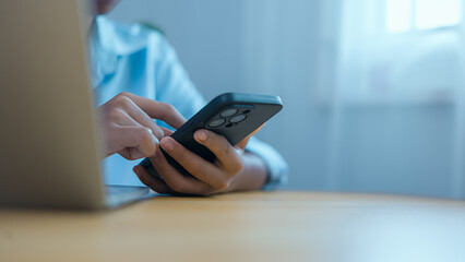 Person Using Smartphone and Laptop for Digital Work and Online Communication