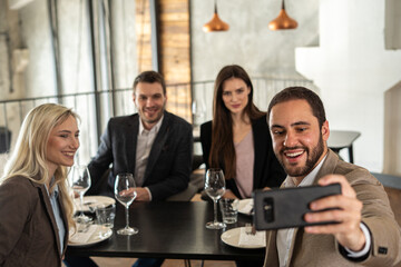 Group of friends taking a selfie at a restaurant during a business lunch