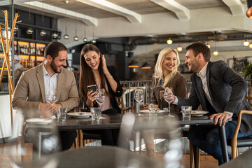 Friends enjoying a meal and sharing a laugh at a stylish restaurant