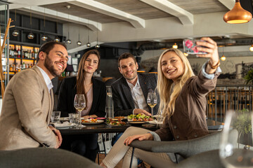 Friends taking a selfie while enjoying a meal at a restaurant