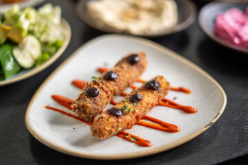 Delicious fried food with sauce and olives on a white plate