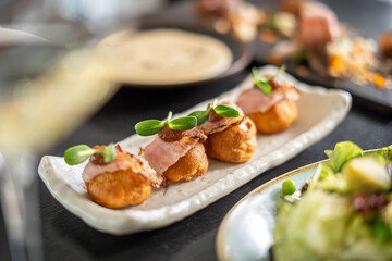 Delicious gourmet appetizers with bacon and microgreens on a white plate