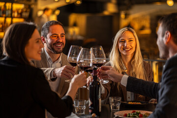 Friends toasting with red wine at a restaurant, celebrating a special occasion