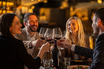 Friends toasting with wine glasses at a restaurant, celebrating a special occasion
