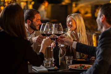 Friends toasting with red wine at a restaurant, celebrating a special occasion