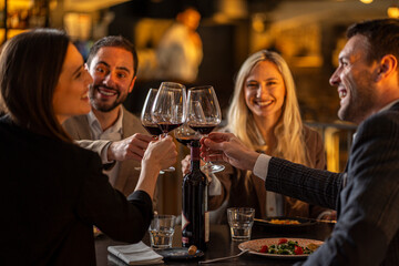 Friends toasting with wine glasses at a restaurant, celebrating a special occasion