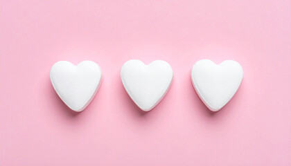 Obraz premium Three white candy hearts on soft pink background, flat lay. Love, relationships and Valentines Day