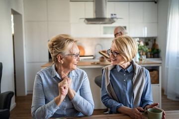 Senior women friends chatting and laughing in kitchen