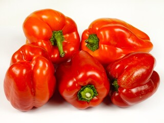 Heap of fresh red bell peppers are on a white board