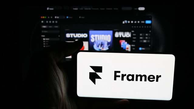 Stuttgart, Germany - 10-27-2025: Person holding mobile phone with logo of Dutch design platform company Framer B.V. on screen in front of web page. Focus on phone display.