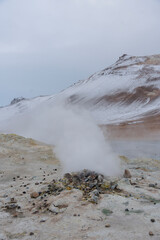 The rugged terrain of Iceland is emitting steam on a cold, misty day.