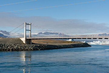 Bridge stretches across Iceland's glacial lagoon with scenic vista background