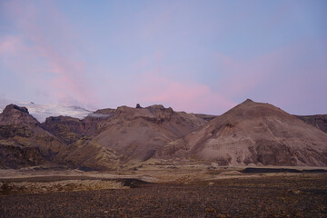 A rocky landscape with mountains and a pink and blue sky background above.
