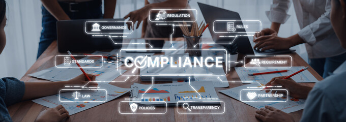 A group of professionals collaborates on compliance strategies using modern technology and visual...