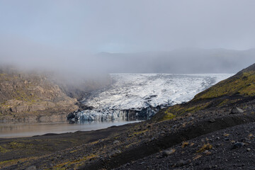 Glacial landscape under a thick fog, black sand beach, and a pristine lake.