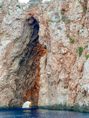 Tall limestone cliff with natural cave opening and water reflection in Mediterranean Sea near Antalya, Turkey. High quality photograph