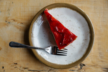 Overhead shot: slice of vibrant red dessert with fork on a speckled plate.